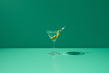 Cóctel de Martini seco con aceitunas sobre fondo verde