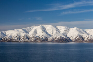 Wall Mural - snow capped mountains on lake sevan in clear weather at sunset