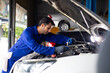 © NVB Stocker - mechanical man working  with tools and spanner. Hispanic latin male mechanic repairs car in garage. Car maintenance and auto service garage concept