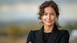 © aicandy - A young woman with a confident smile, dressed in a black blazer, standing outdoors with a blurred natural background, exuding confidence and poise