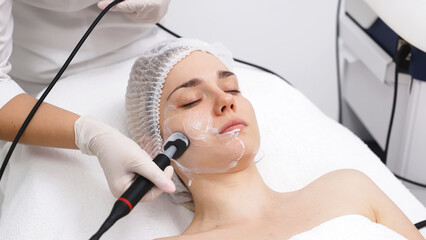 A cosmetologist applies radiofrequency lifting to a young woman in a modern clinic. This advanced procedure tightens skin and promotes rejuvenation, ideal for showcasing beauty treatments.