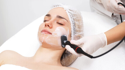 A cosmetologist applies radiofrequency lifting to a young woman in a modern clinic. This advanced procedure tightens skin and promotes rejuvenation, ideal for showcasing beauty treatments.