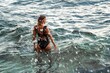 © svetograph - Woman Swimsuit Ocean Water - Woman in a black swimsuit wading in the ocean water.