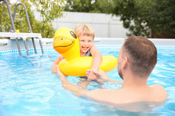 Wall Mural - Happy daughter and her father having fun in swimming pool