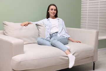 Wall Mural - Smiling woman relaxing on sofa at home