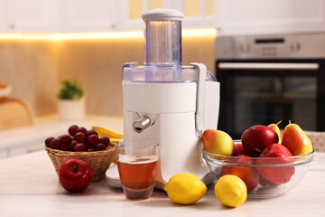 Modern juicer, fresh fruits and glass on white marble table in kitchen