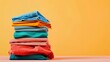© VK Studio - A vibrant stack of folded clothes in various colors against an orange background, evoking a sense of freshness and organization.