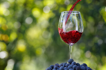 red wine pouring into glass with green background