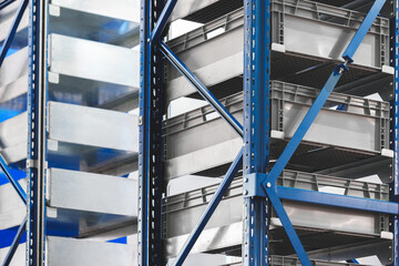 Fototapete - Blue and silver shelving unit with shelves and gray plastic boxes in modern warehouse, bottom up view, logistics concept