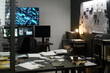 © pressmaster - Modern office filled with devices and paperwork, showcasing various screens and detailed notes pinned on wall, indicating high-tech investigative work environment