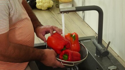 Wall Mural - Man is washing red pepper at the kitchen