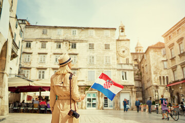 Wall Mural - Enjoying vacation in Croatia. Young traveling woman with national croatian flag walking on Split Old Town.