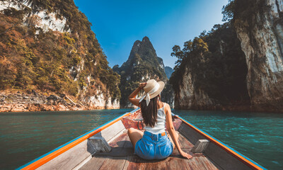 Wall Mural - Traveler asian woman relax and travel on Thai longtail boat in Ratchaprapha Dam at Khao Sok National Park Surat Thani Thailand