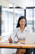 © David - Asian Businesswoman Using laptop computer and working at office with calculator document on desk, doing planning analyzing the financial report, business plan investment, finance analysis concept.