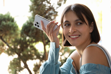 Poster - Beautiful woman with smartphone listening to voice message outdoors