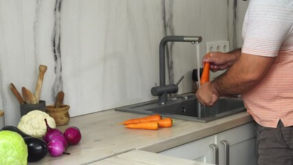 Wall Mural - Man is washing carrot for cooking at the kitchen