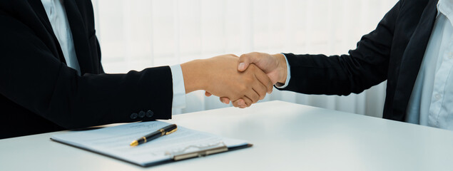 Wall Mural - Two business executive shake hand in boardroom, sealing agreement merging two company. Handshake symbolize business partnership and cooperation. Corporate acquisition and merger concept. Shrewd