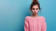 © Deris Firmansyah - A young woman with an angry expression, wearing a pink sweater against a blue background.