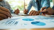 © Ganesha - A close-up of a business team working together to discuss work. Analyzing with financial data and graphs of marketing growth reports in the team.