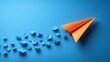 © Helois - A single orange paper airplane leading a group of blue paper airplanes on a blue background.