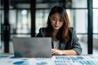 © Fotograf - A woman sitting at a table with a laptop, possibly doing work or studying
