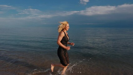 Poster - Young happy woman in black dress running on water on summer day, slow motion