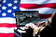 © DC Studio - United States military officer using target acquisition software on notebook to detect enemy location. Close up shot of soldier isolated over USA flag using satellite gear to identify terrorists