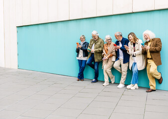 Happy senior adult people using smart phone leaning over blue background