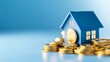 © NEW - A blue house model sitting on a pile of gold coins, representing real estate investment and financial growth.