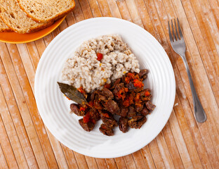 Barley porridge with chicken hearts on a plate