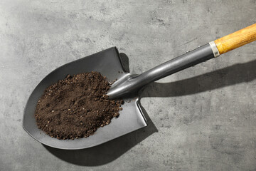 Wall Mural - Metal shovel with soil on grey table, top view