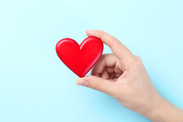 Wall Mural - Woman with red heart on light blue background, closeup