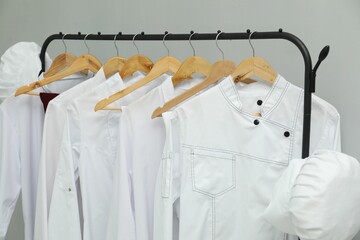 Wall Mural - Chefs' uniforms on clothing rack against grey background