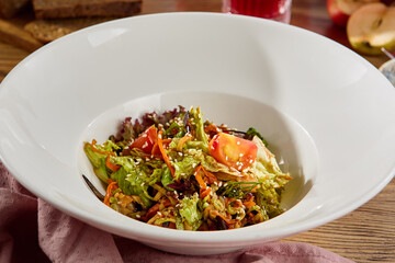 Wall Mural - Fresh Vegetable Salad with Lettuce, Tomato, and Carrot in a White Bowl on a Wooden Table