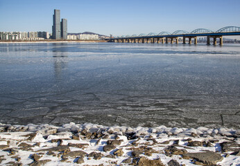 Dongjak-gu, Seoul, South Korea - January 8, 2021: Frozen Han River with ice with the background of Dongjak Bridge and high rise apartments