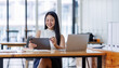 © David - Business asian woman or female worker using a laptop computer to analyse her financial data.business people research or financial strategy in company concept. Laptop white screen mockup.