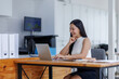 © David - Business asian woman or female worker using a laptop computer to analyse her financial data.business people research or financial strategy in company concept. Laptop white screen mockup.