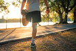 © oatawa - Close up - Man runner stretching leg and feet and preparing for jogging and running in public park outdoors at sunset, Active and healthy lifestyle concept, copy space
