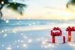 © mashimara - Wrapped gifts tied with red bows resting on sandy tropical beach at sunset, with festive lights and blurred palm trees in the background.