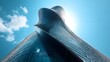 © Wira - Low-angle view of a modern glass building with a sleek, curved design against a clear blue sky. The reflective windows and fluid architecture create a sense of innovation and futuristic.