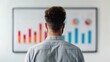 © JewJew - A man looks at colorful bar and pie charts on a presentation screen, analyzing business data and trends.