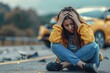 © Igor - a close up upset person sitting on the road against the background of her car, which was wrecked in an accident
