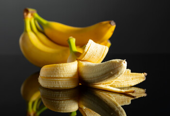 Poster - Ripe juicy bananas on a black reflective background.