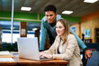 © SometimesNever/peopleimages.com - Students, man and woman with laptop, education and library with notes for learning, development and research. Person, happy and partner with reading, scholarship and studying in hall at university