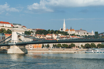 view of the old town of buda from chain bridge with stone tower on the left and danube river with huge boat passing by