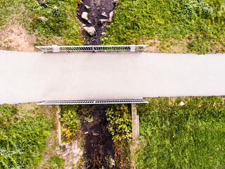 Aerial view of running path, jogging trail with bridge in the middle of park. Running training, no people.