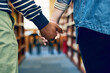 © SometimesNever/peopleimages.com - Couple, students and closeup for holding hands in library with support, care and education at university. People, learning and together for scholarship, research or studying with partner at college