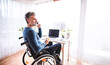 © Halfpoint - Handsome man in wheelchair working from home office, making phone call. Telecommuting and home office.