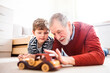 © Halfpoint - Boy and grandpa lying on floor, playing with car model. Grandfather spending time with grandson, taking care of him while parents are at work.