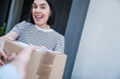 © Westend61 - Happy woman receiving parcel from delivery person outside house